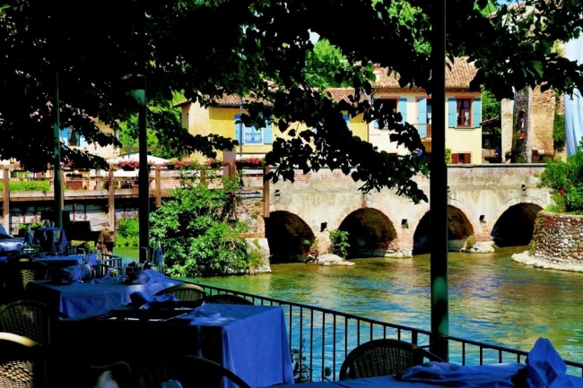 Trattoria intima sotto un pergolato in riva al Mincio